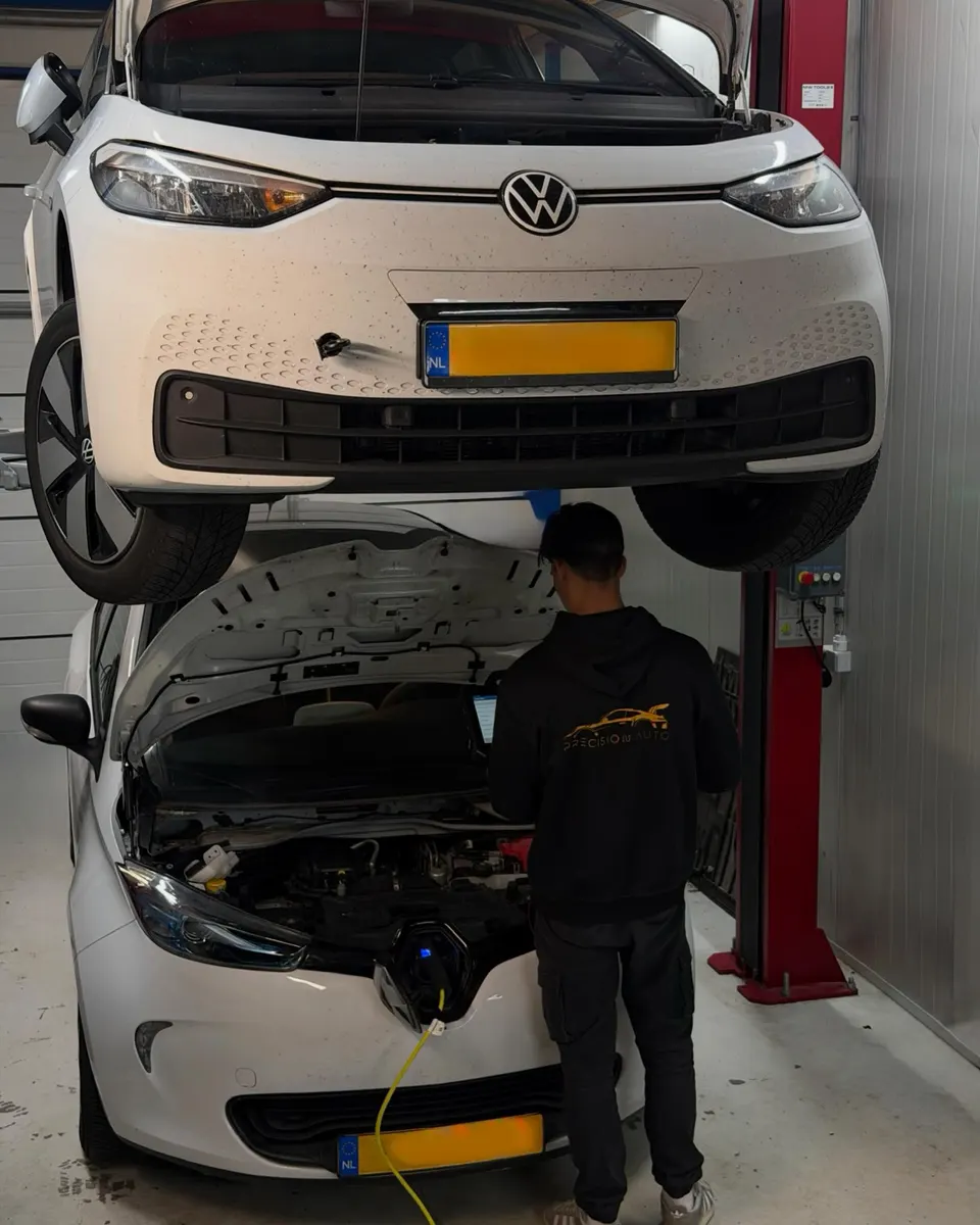 Monteur van PrecisionAuto aan het werk in de werkplaats, met een VW ID. op de brug erboven